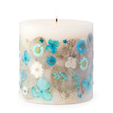 Pillar candle with pressed blue and white flowers decorating the sides.