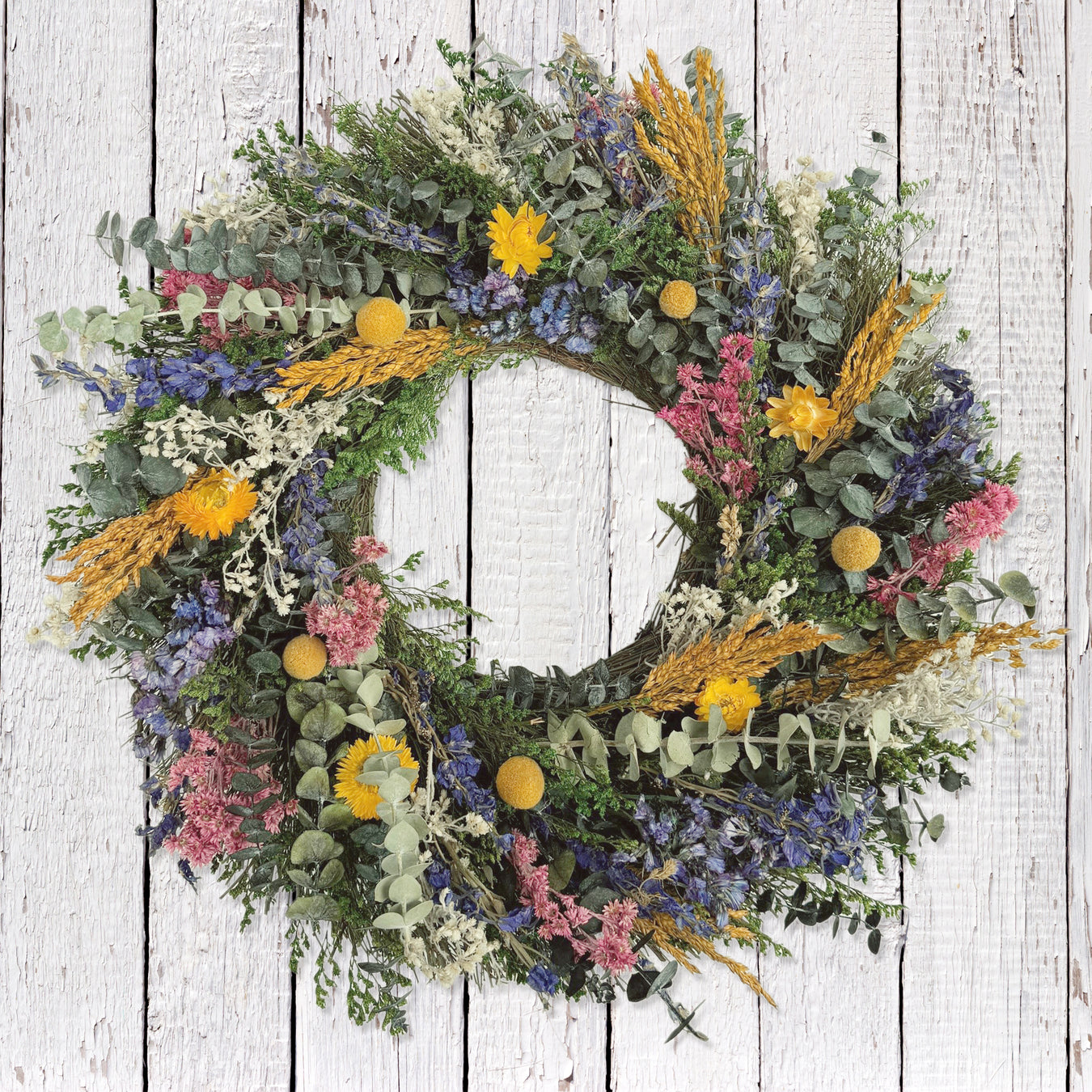 Colorful wreath made of natural botanicals such as baby eucalyptus, straw flowers, and sorghum.