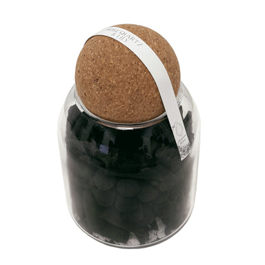 Black incense cones in glass jar with cork lid.