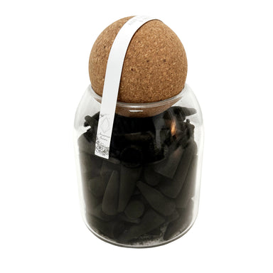 Black incense cones in glass jar with cork lid.