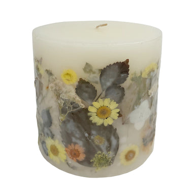 Ivory pillar candle with delicate pressed flowers in yellow and white along with green leaves decorating the outside of the candle.