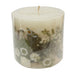 Ivory pillar candle with delicate white pressed flowers and green leaves decorating the outside of the candle.