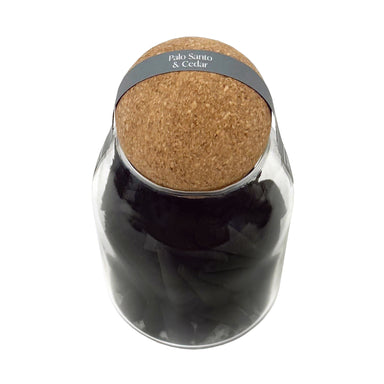 Black incense cones in glass jar with cork lid.