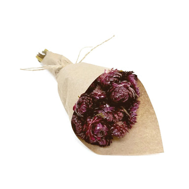 Bouquet of purple flowers wrapped in brown paper on a white background