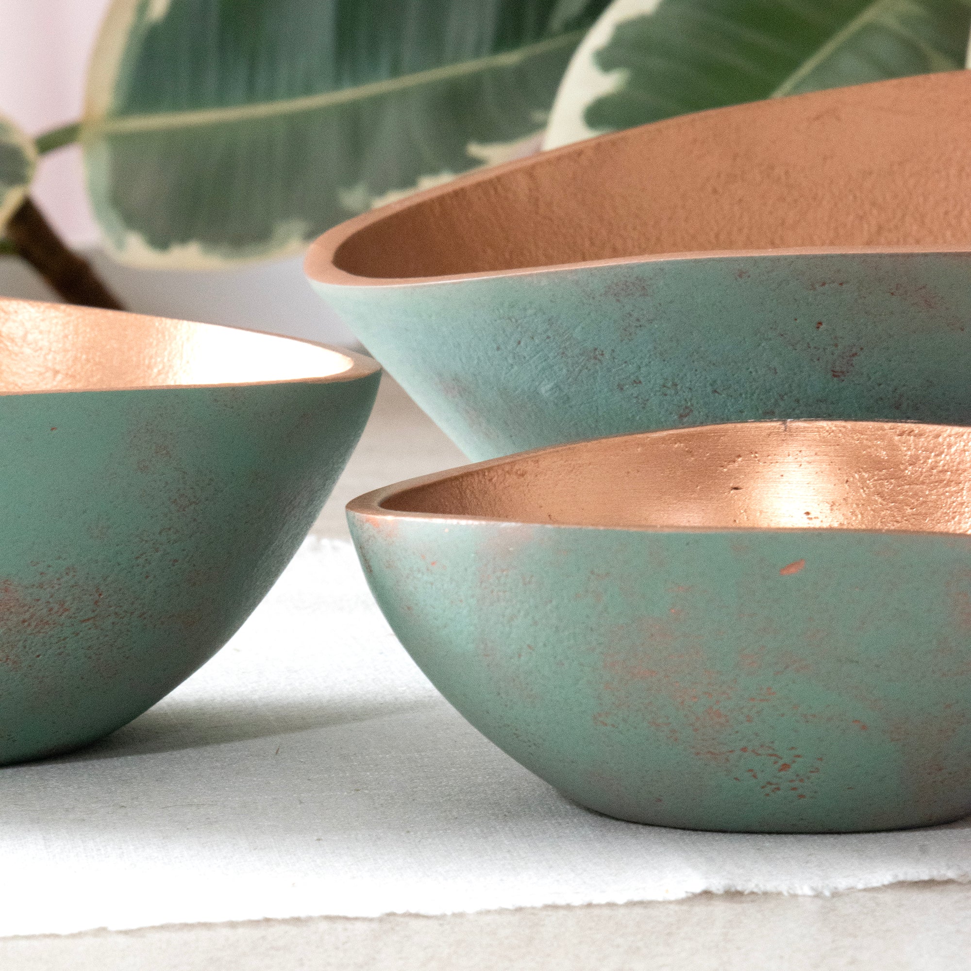 Close up of the Set of 3 Turquoise Copper Cast Metal Decorative Bowls, empty bowls in room setting.