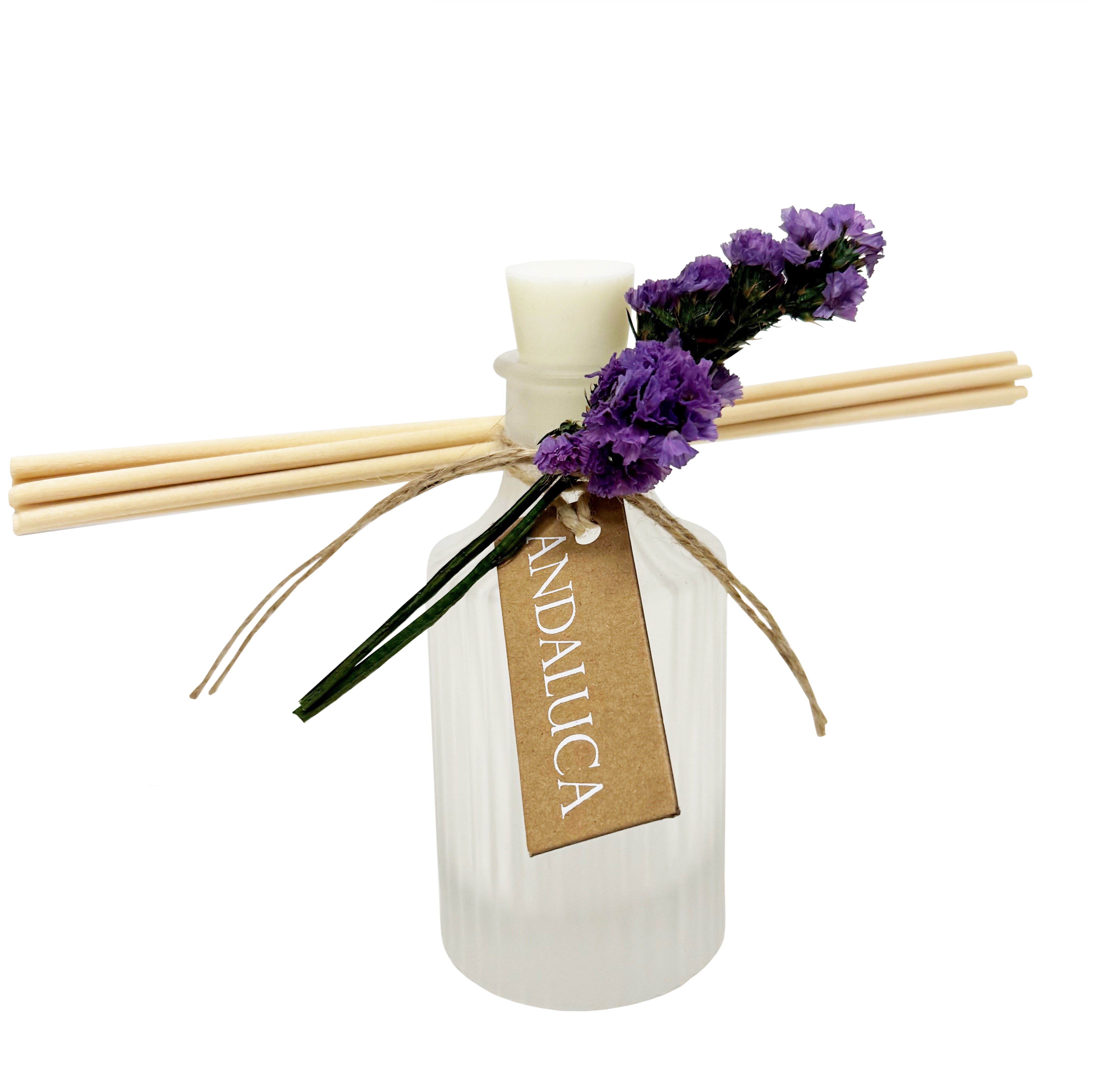 Frosted ridge glass diffuser with reeds and a purple flower tied to the bottle.