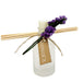 Frosted ridge glass diffuser with reeds and a purple flower tied to the bottle.