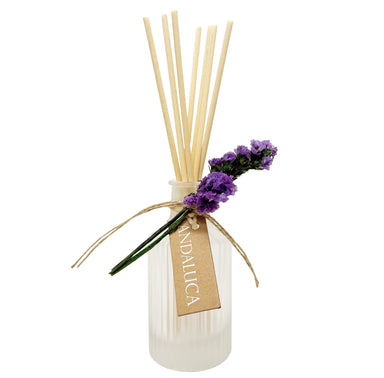 Frosted ridge glass diffuser with reeds and a purple flower tied to the bottle.