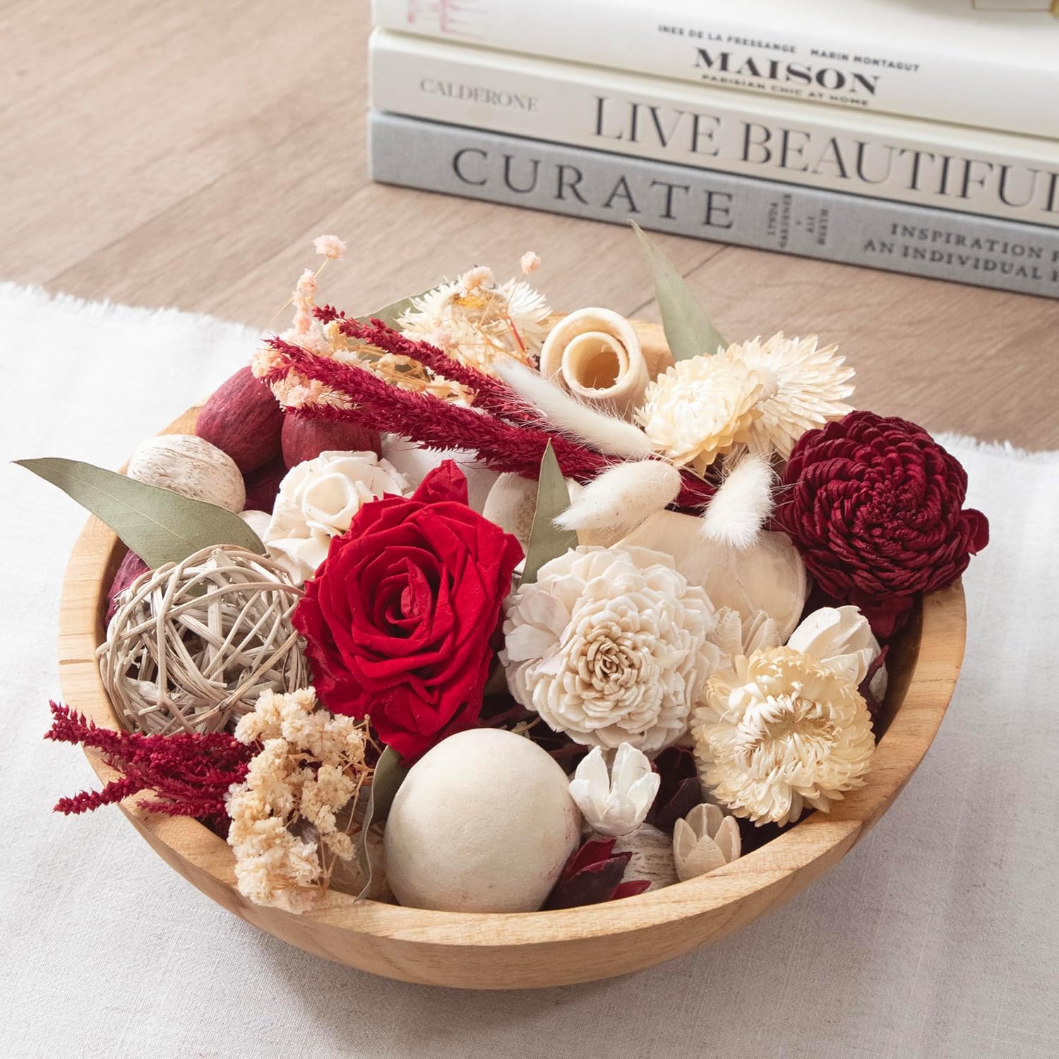 Wooden bowl with red and white flowers on a light surface with books in the background