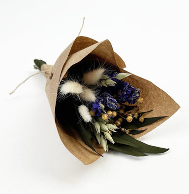Mini bouquet with purple larkspur, willow eucalyptus, bunny tails, flax, and aveena in kraft paper wrap with jute tie.