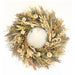 A circular dried floral wreath made of natural beige, tan, and olive green botanicals, including grasses, small flowers, and seed pods, photographed against a plain white background.