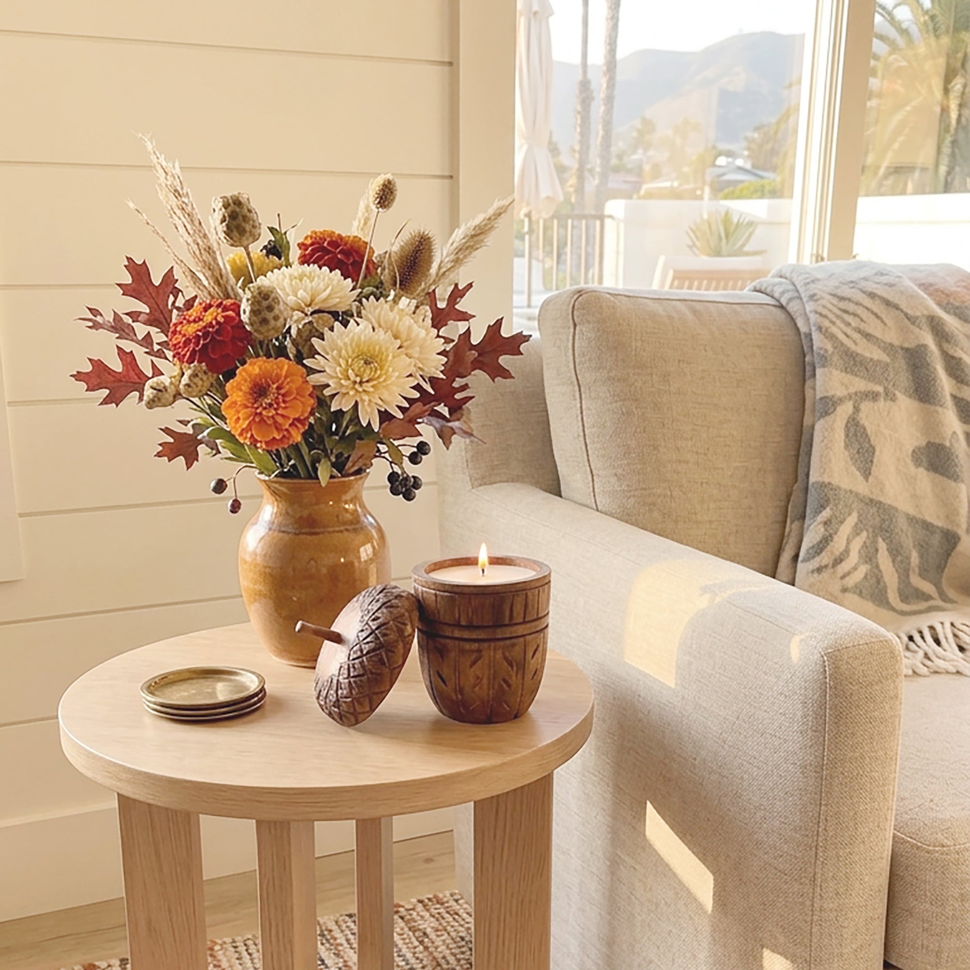 Acorn Wood Candle lit on a side table in a living room.