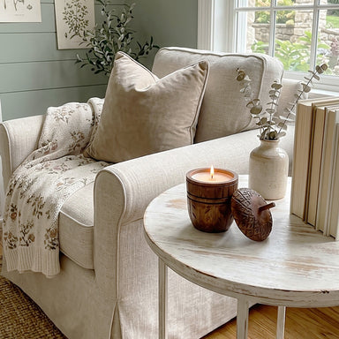 Acorn Wood Candle lit on a side table in a living room.