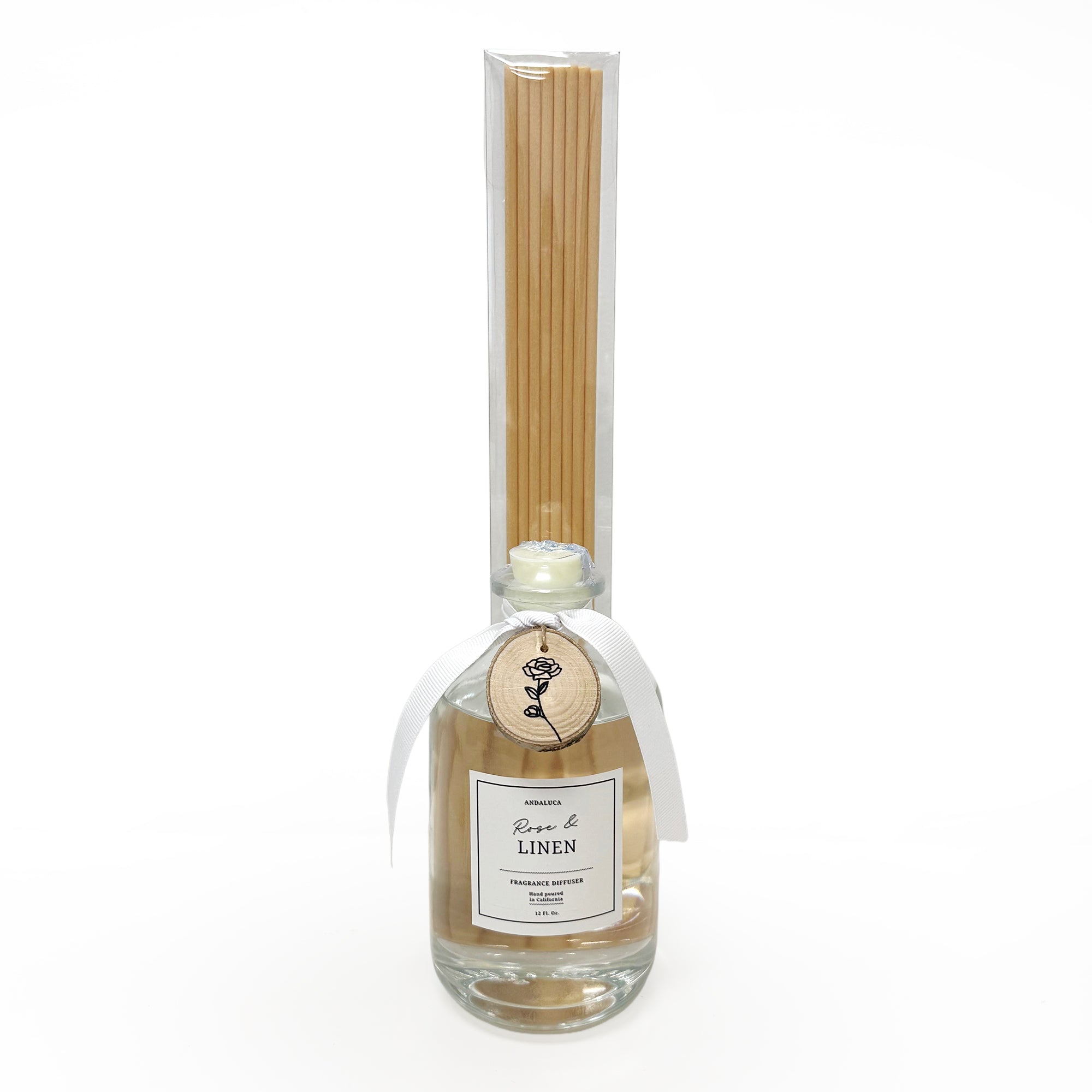 Glass reed diffuser with reeds attached to bottle and wood charm around bottle neck.