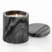 Marble-patterned candle holder with a lit candle on a white background