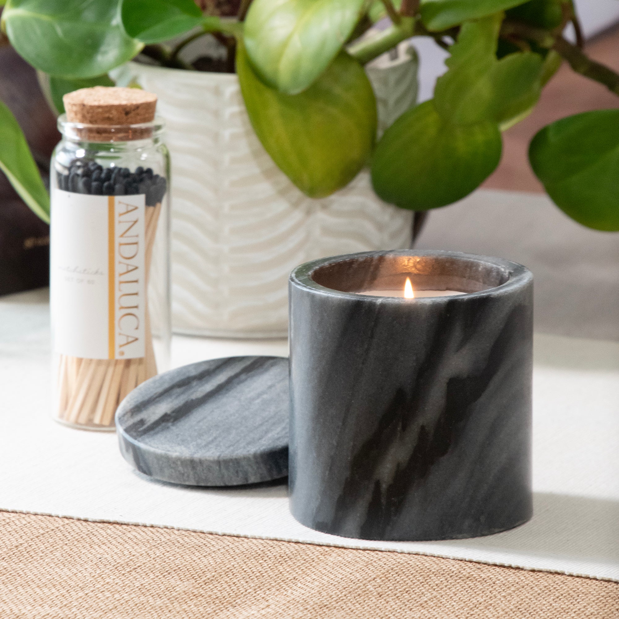 A Palo Santo Scented Black Marble Candle, burning on a table top.