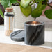 A Palo Santo Scented Black Marble Candle, burning on a table top.