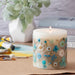 Pillar candle with pressed blue and white flowers decorating the sides.