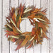 Burnt Orange Autumn Wreath, on a whitewashed fence background.