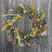 Colorful wreath made of natural botanicals such as baby eucalyptus, straw flowers, and sorghum.