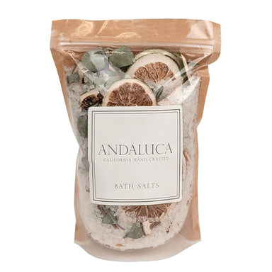 A stand-up resealable pouch of Andaluca California Hand Crafted Bath Salts, filled with coarse white salt crystals and dried citrus slices, green leaves, and herbs, set against a plain white background.