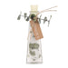 A clear glass bottle with a cream-colored stopper, filled with white sand or salt, green eucalyptus leaves, and a brown kraft paper tag tied with twine. The tag reads 'ANDALUCIA'.