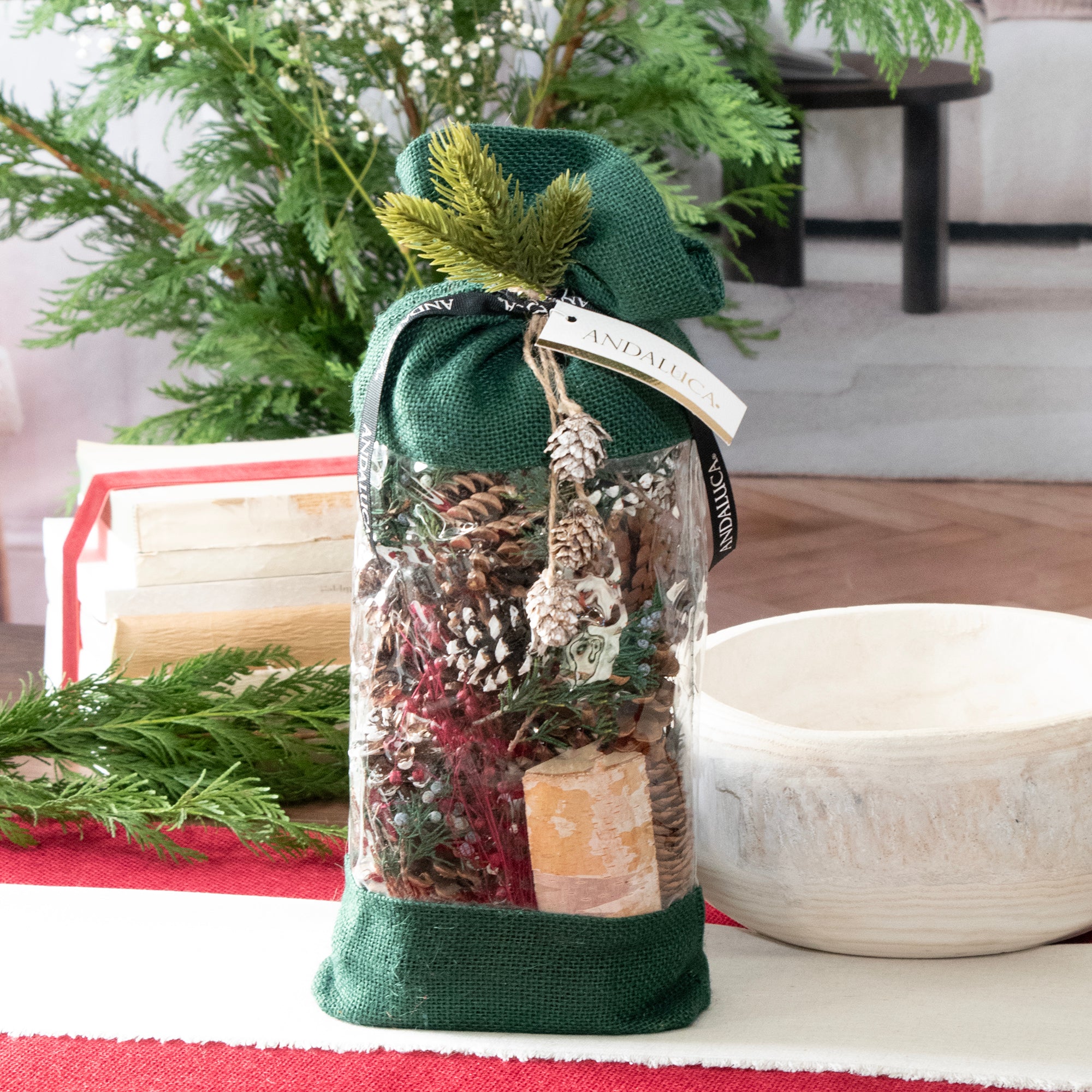 Evergreen Pine Burlap Pinecone Bag. It is a green drawstring bag filled with natural elements, shot on a table.