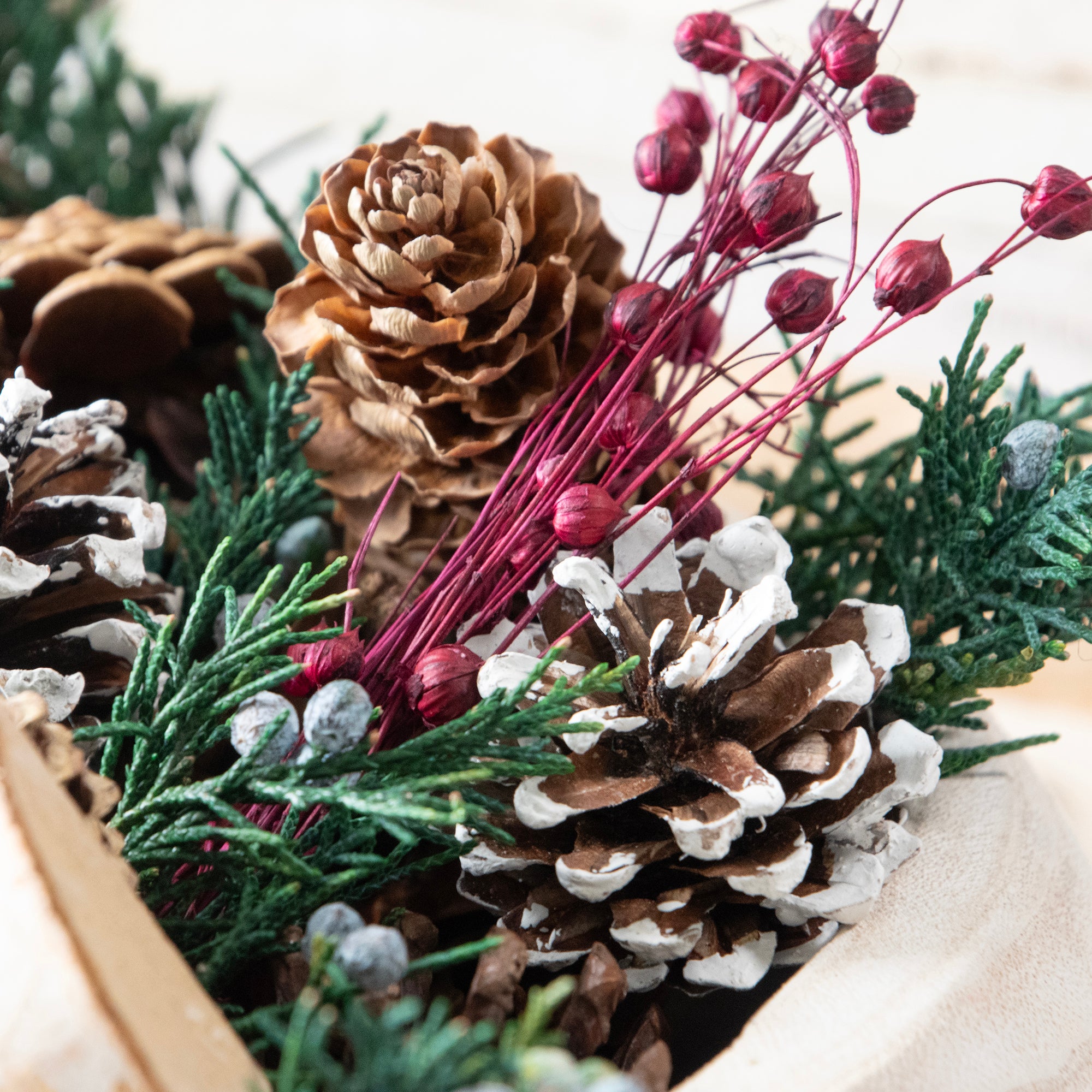 Close up of the botanicals in the Evergreen Pine Burlap Pinecone Bag. Displayed in a white wooden bowl, shot on a table.