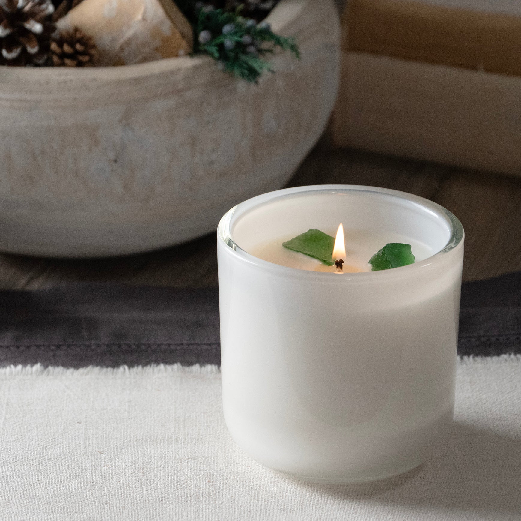 Lite white glass candle vessel with 3 green translucent stones placed in the wax surounding the wick. Stones do not need to be removed while burning.