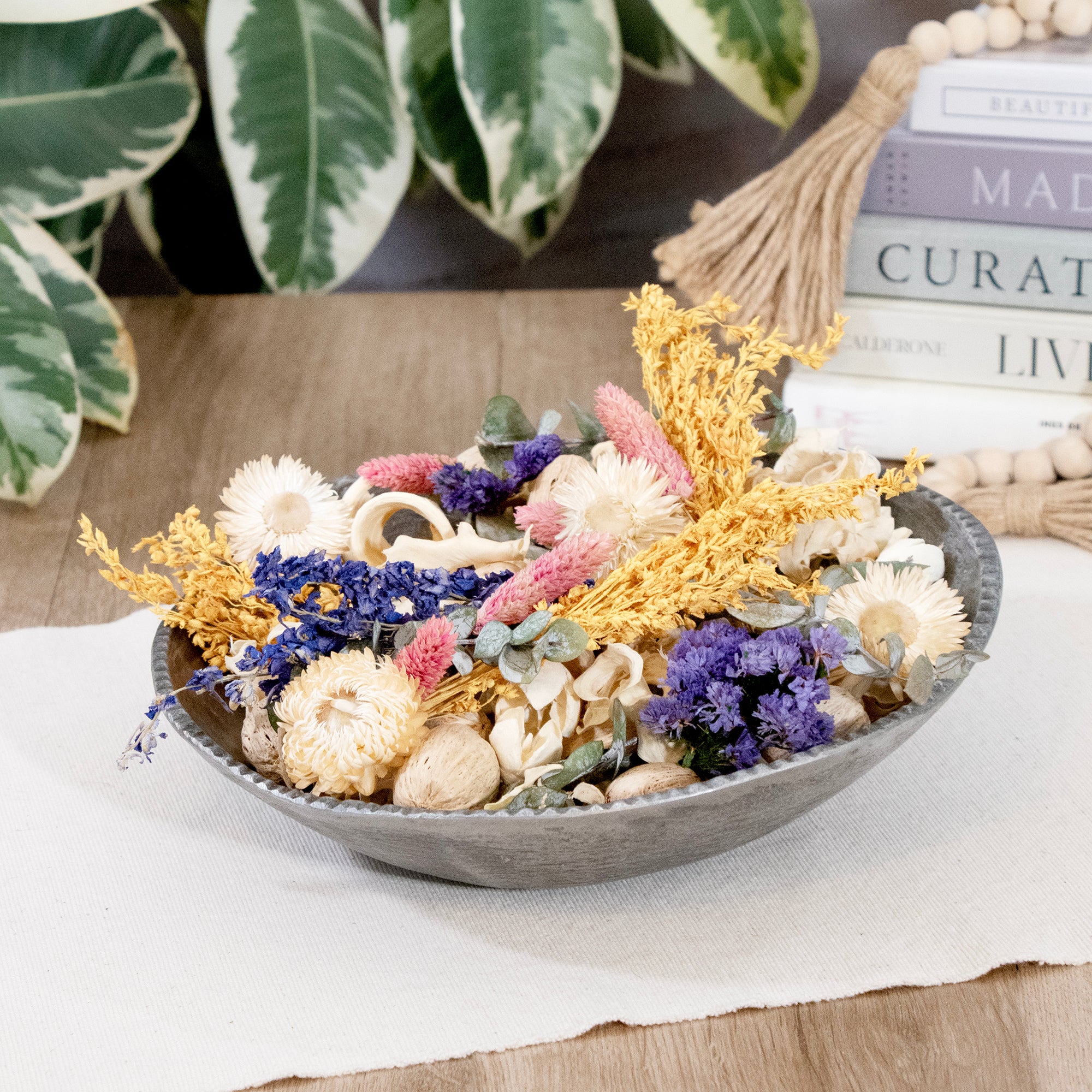 Decorative bowl with dried flowers and seashells on a wooden surface