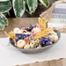 Decorative bowl with dried flowers and seashells on a wooden surface