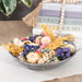 Decorative bowl with dried flowers on a surface with books in the background