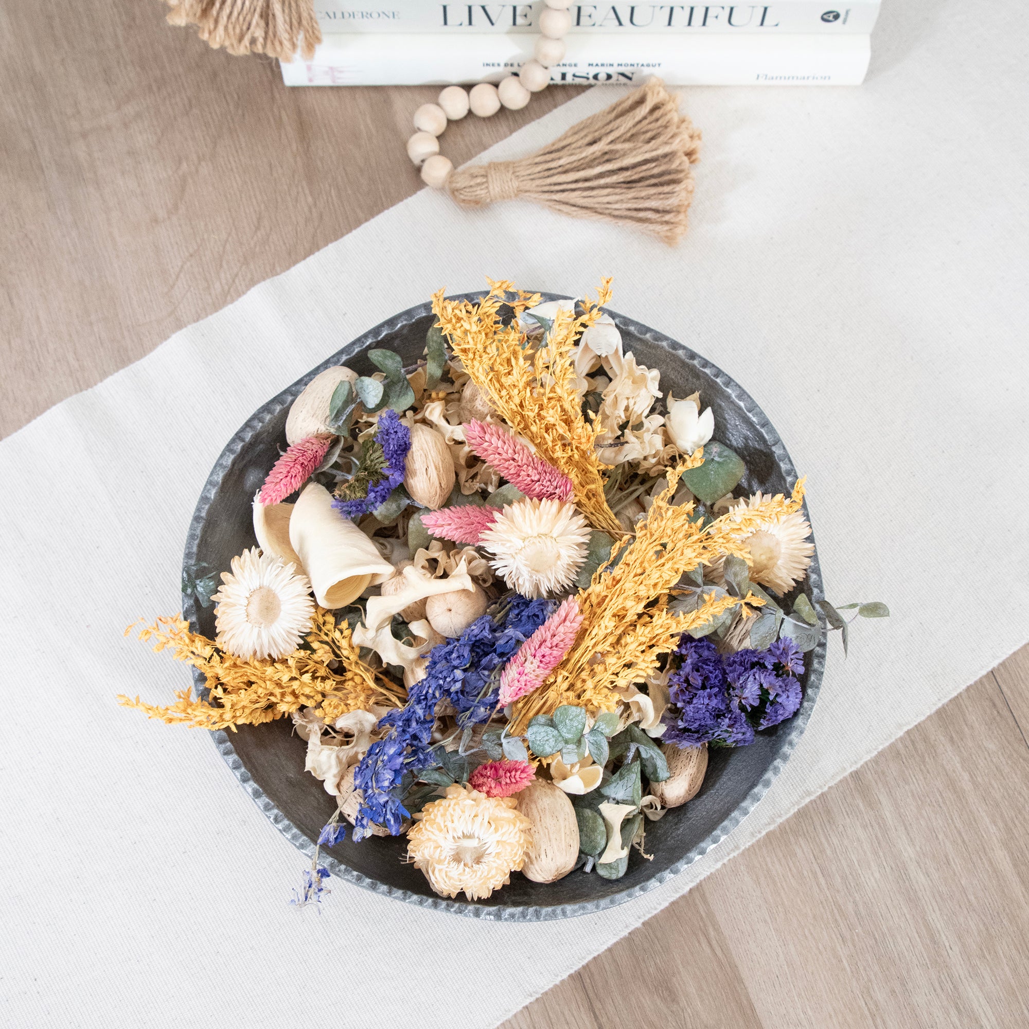 Decorative plate with dried flowers on a light wooden surface