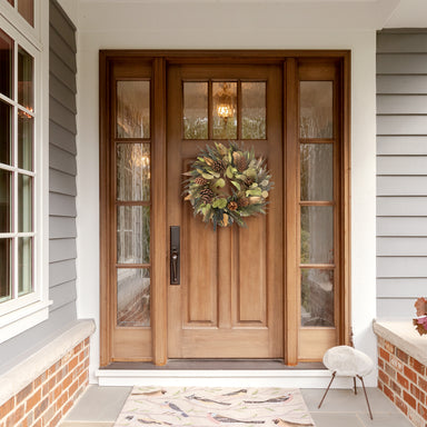 Gold Patina Wreath hanging on a wooden exterior house front door.