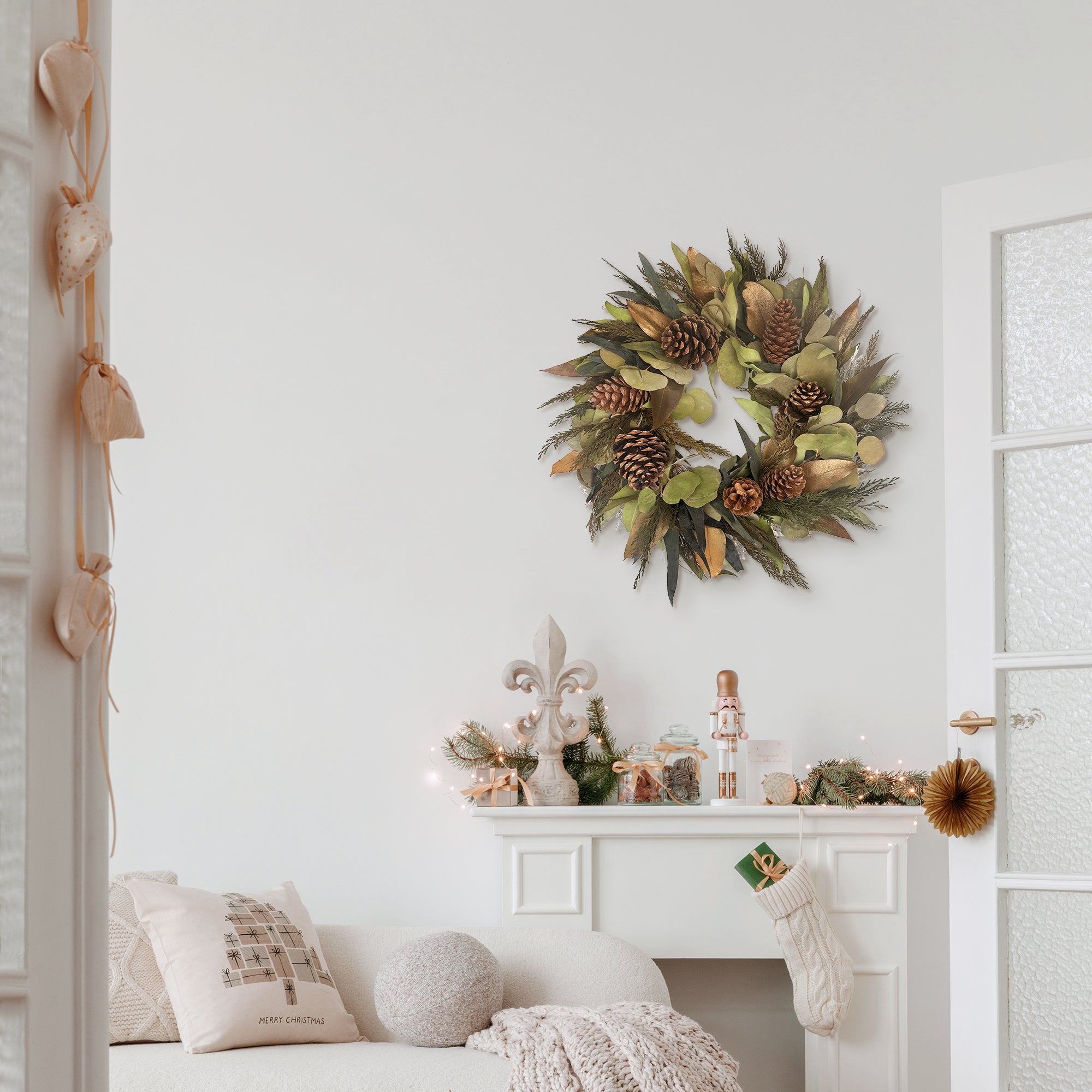 Gold Patina Wreath hanging on a wall above a fireplace with festive decorations.