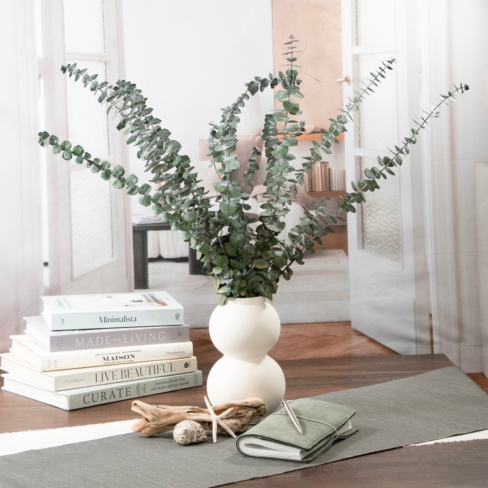 Green Baby Eucalyptus Preserved Bundle in a vase, set on a table.