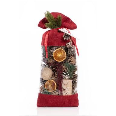 Holiday Memories Burlap Pinecone Bag is a decorative potpourri bag with red burlap fabric on the top & bottom. The bag is clear in the middle allowing it to act as a window to the content of pine cones, oranges, and other botanicals. Shot on a white background.