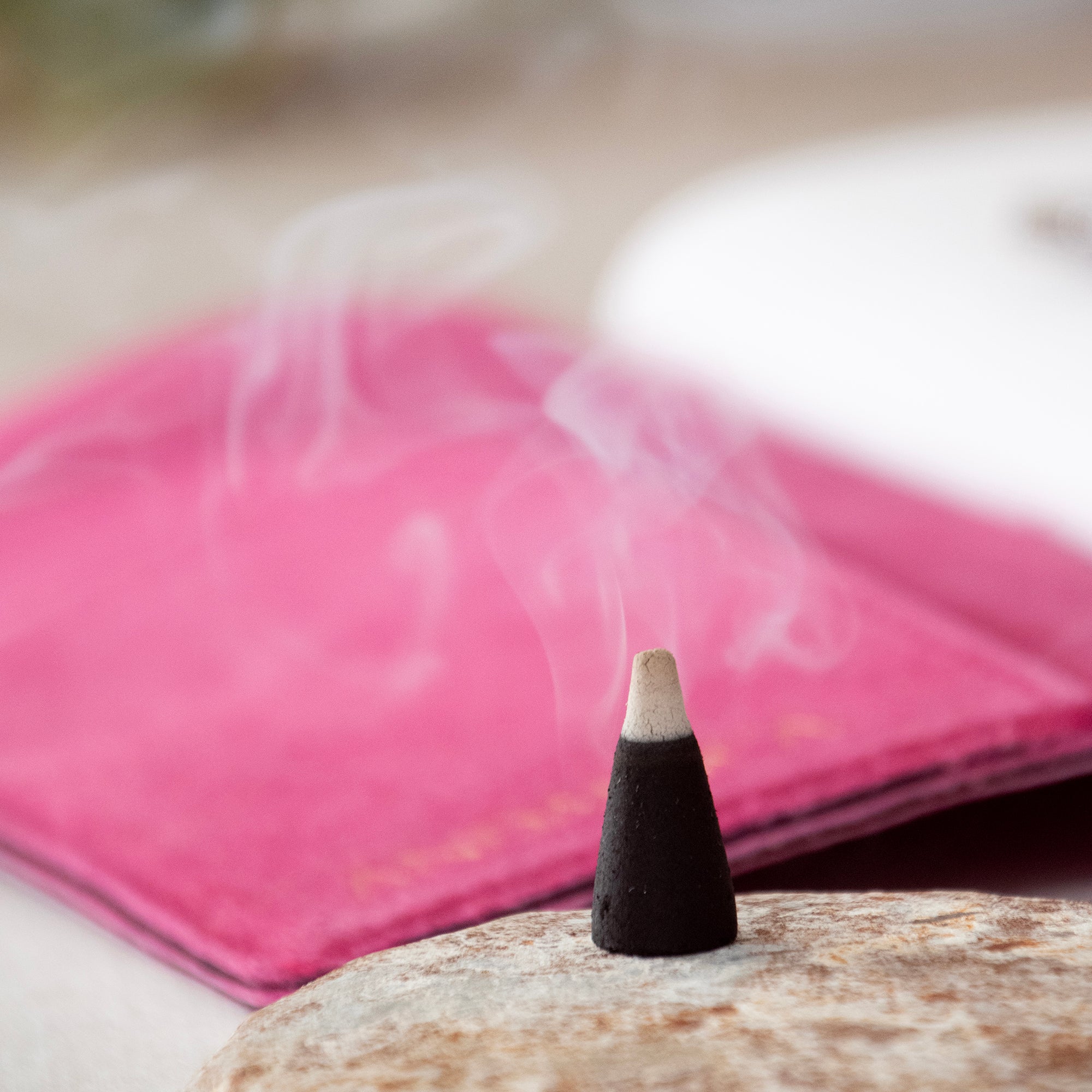 Burning black incense cone, in a lifestyle setting.