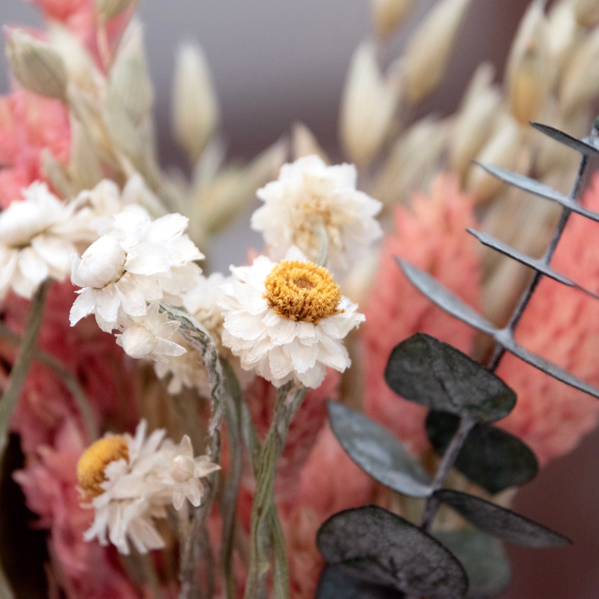 Close up of Mini bouquet with pinl larkspur, willow eucalyptus, baby eucalyptus, phalaris, and aveena.
