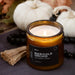 Marigold Orchid burning candle with pumpkins and leaves in the background.