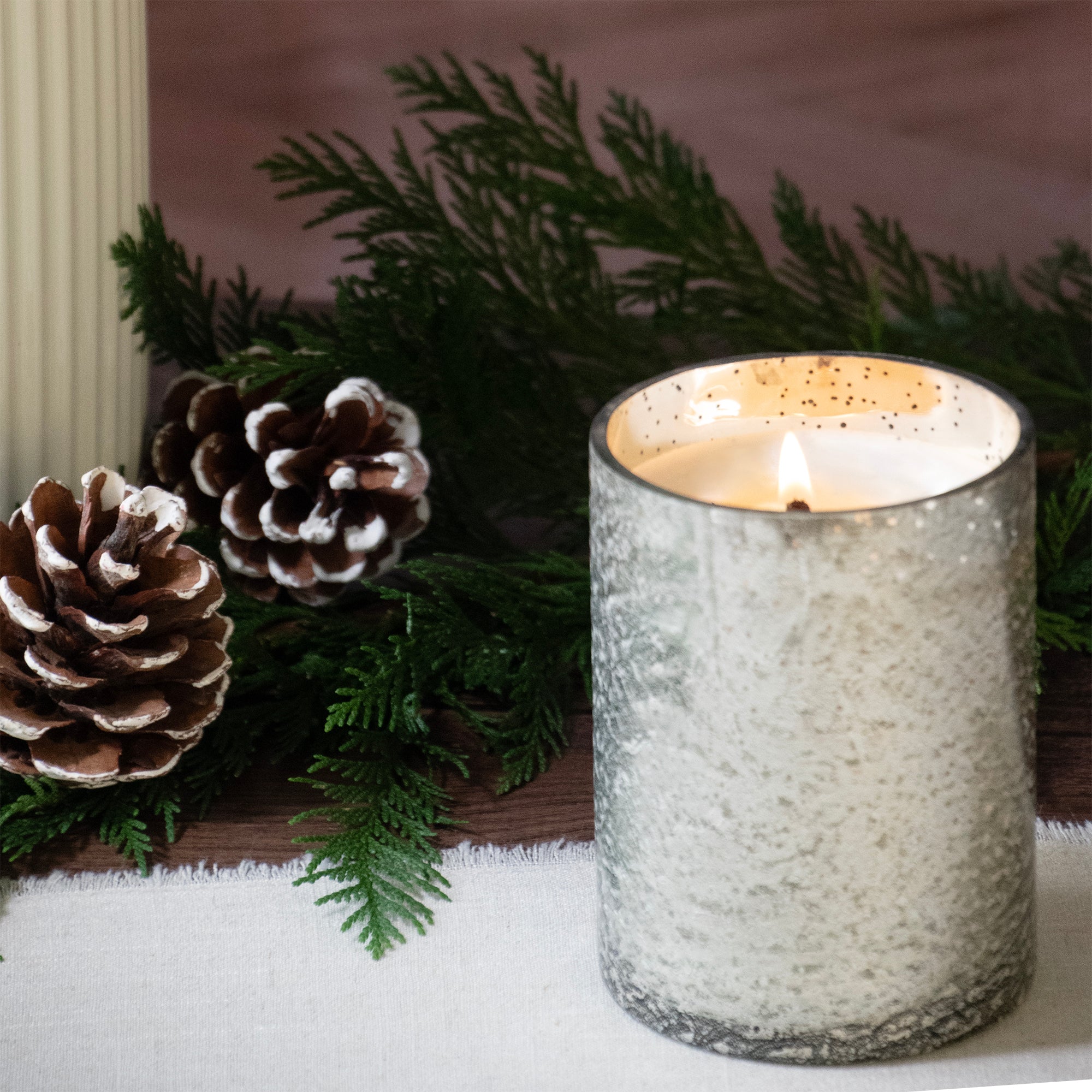 Mercury candle cup lit, set on a table top.