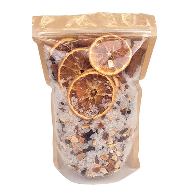 A clear resealable stand-up pouch with a kraft paper top, filled with coarse salt crystals and dried orange slices, photographed on a plain white background.