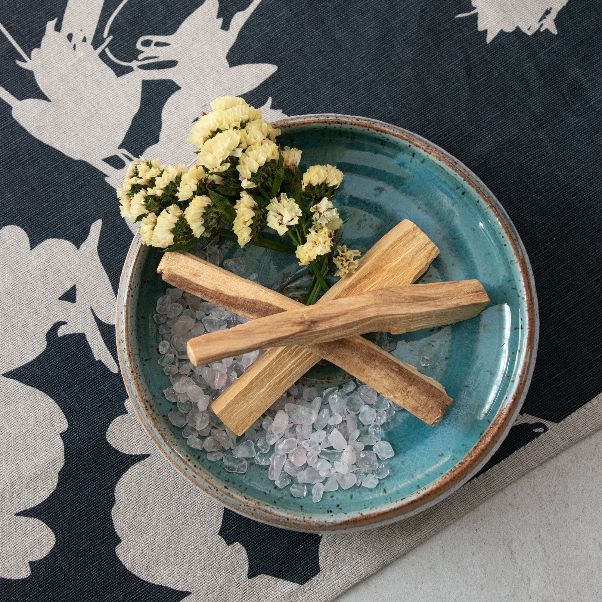 Contents of the Palo Santo & Yellow Flower Smudging Jar Set, displayed in a ceramic dish.