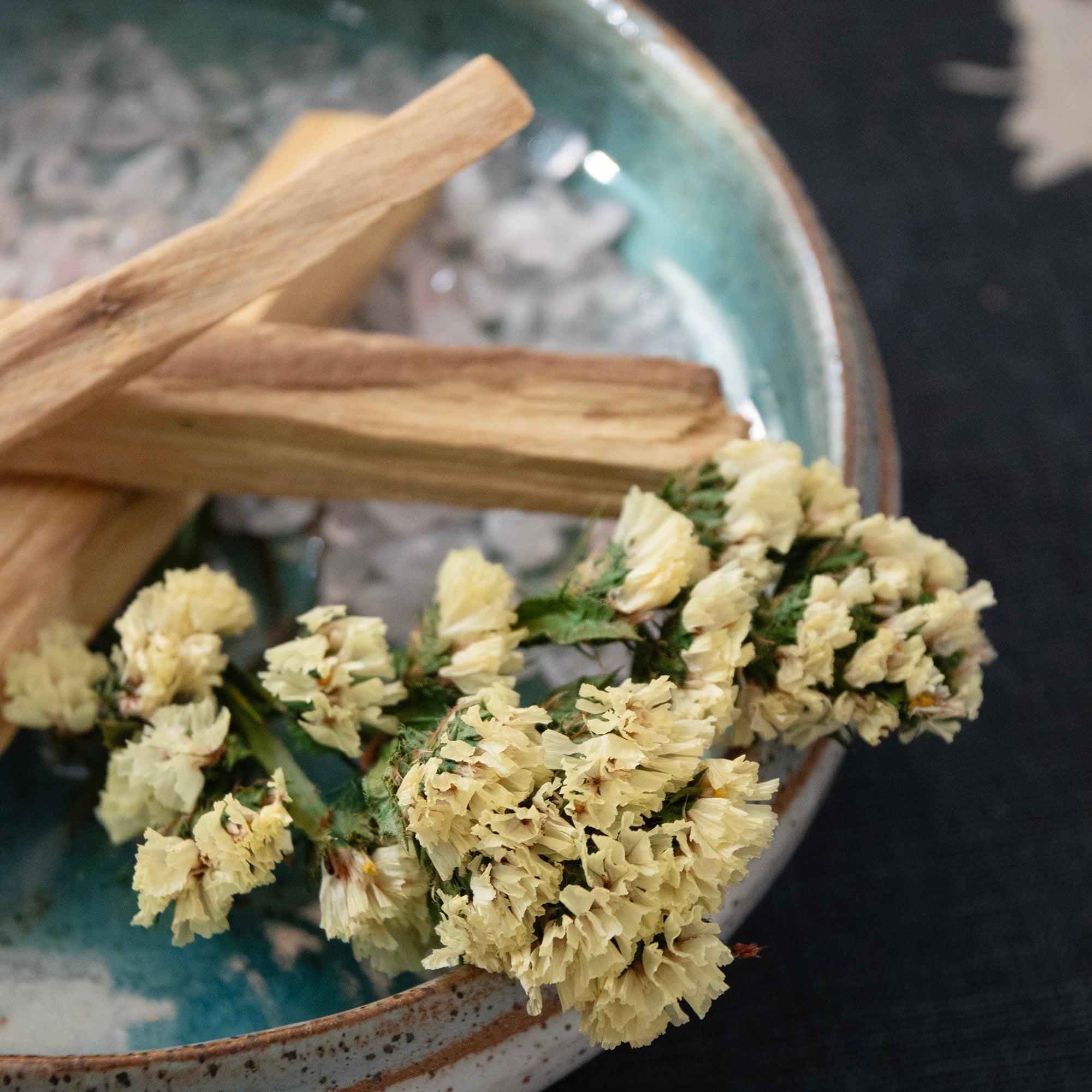 Close -up of the  Palo Santo & Yellow Flower Smudging contents, displayed in a ceramic dish.