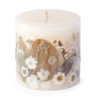 Ivory pillar candle with delicate white pressed flowers and green leaves decorating the outside of the candle.