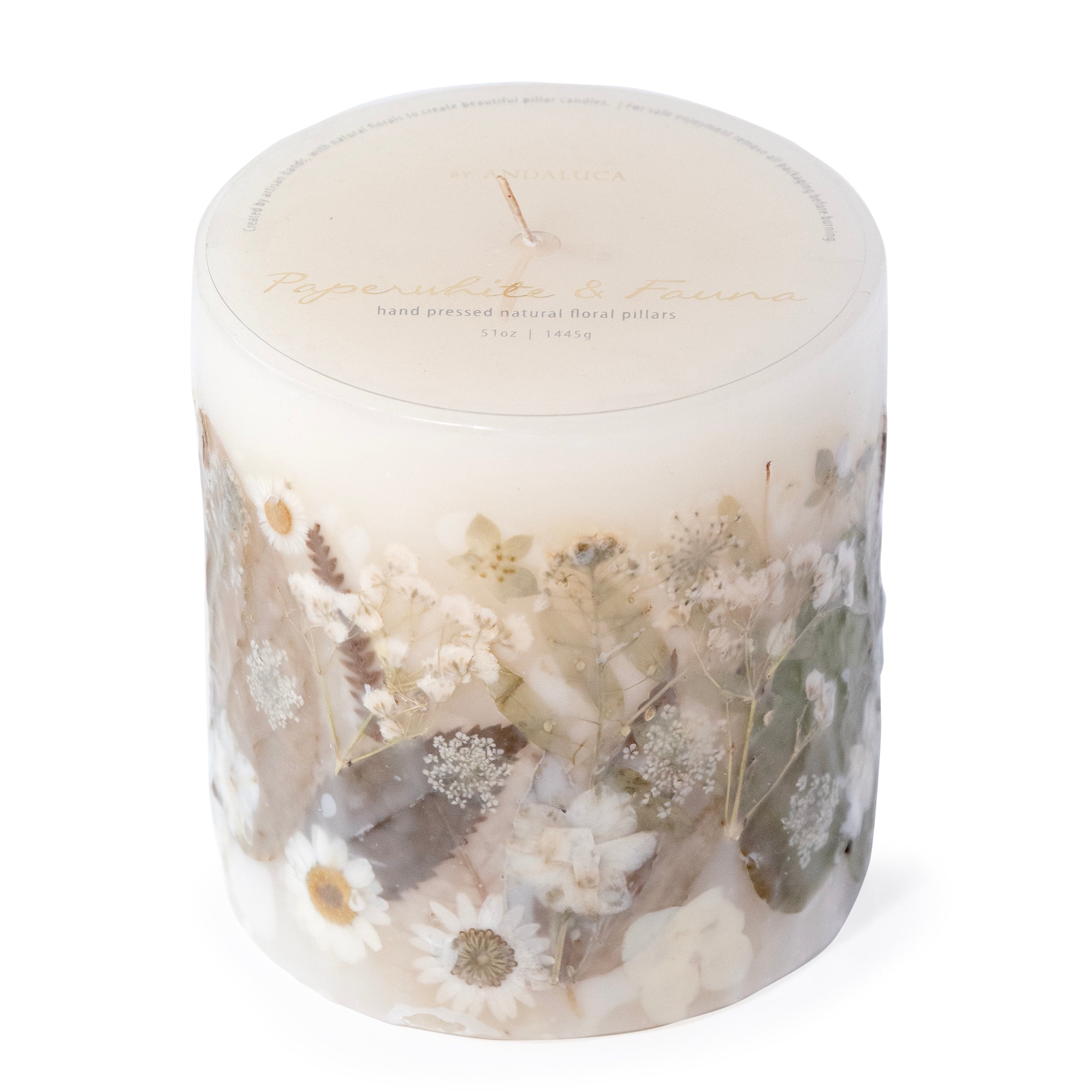 Ivory pillar candle with delicate white pressed flowers and green leaves decorating the outside of the candle.