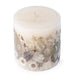 Ivory pillar candle with delicate white pressed flowers and green leaves decorating the outside of the candle.