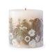 Ivory pillar candle with delicate white pressed flowers and green leaves decorating the outside of the candle.