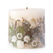 Ivory pillar candle with delicate white pressed flowers and green leaves decorating the outside of the candle.