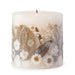 Ivory pillar candle with delicate white pressed flowers and green leaves decorating the outside of the candle.